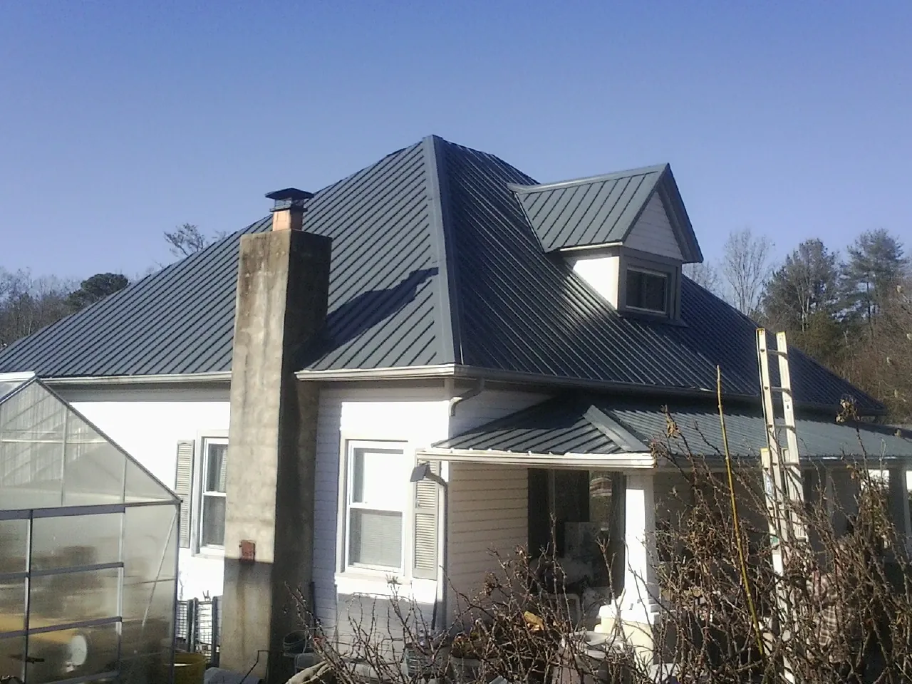 Dark blue standing seam metal roof on a white farmhouse with dormer — Slate & Tile Roof Repair by Roofing Brothers in Tazewell