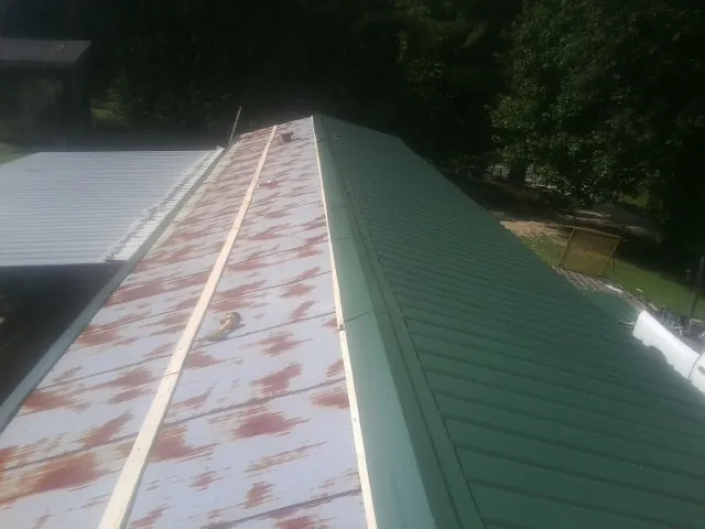 Old rusted panels beside newly installed green metal roofing — Wind Damage Roof Repair by Roofing Brothers in Tazewell
