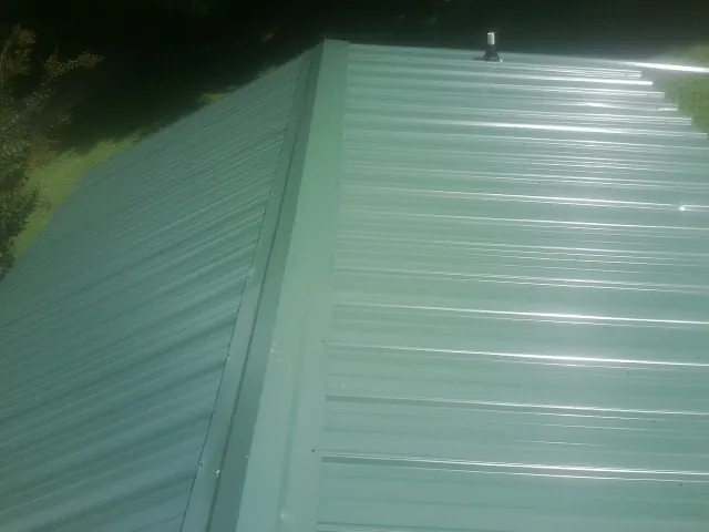 New green metal panels meeting at the ridge of a roof — Flat Roof Repair work by our crew in Tazewell