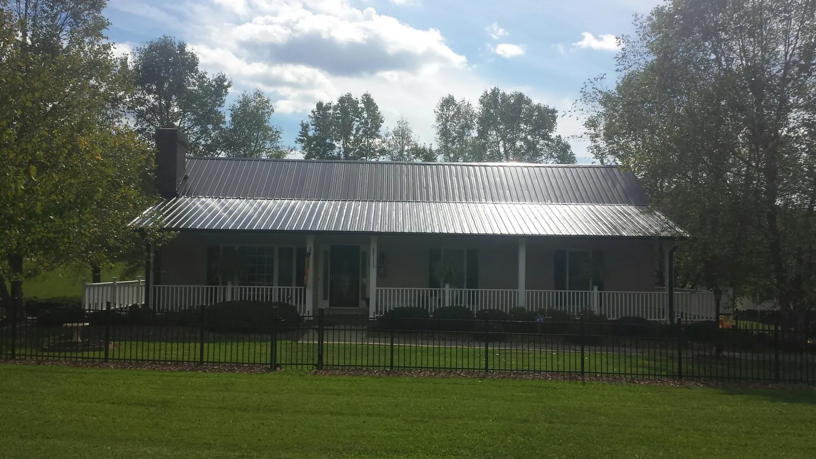 Gray metal roof on a brick ranch with a full width front porch — Gutter Guard Installation work by our crew in Tazewell