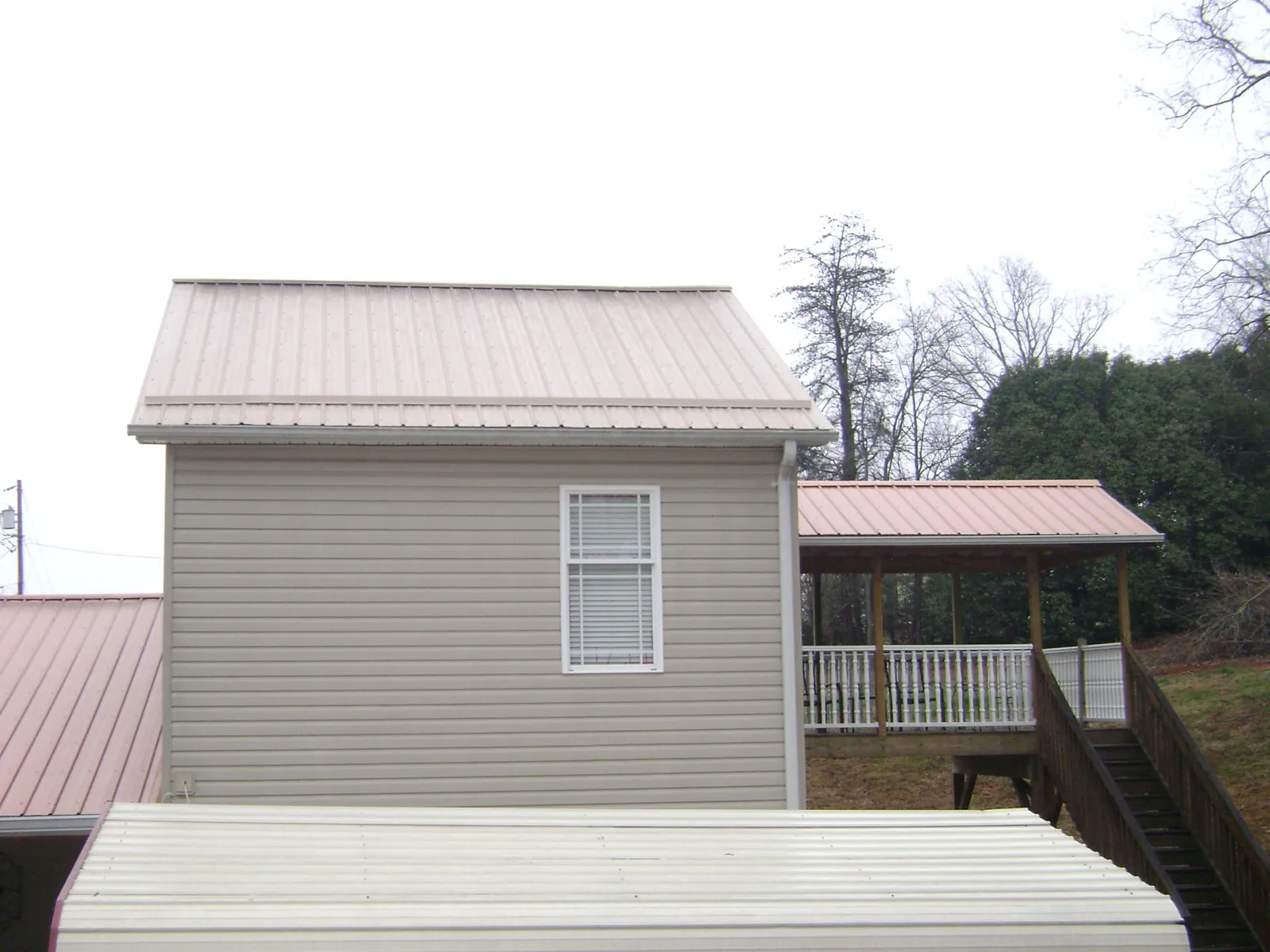 Tan metal roofs on a two story addition and attached porch, from a Roof Replacement job in Tazewell